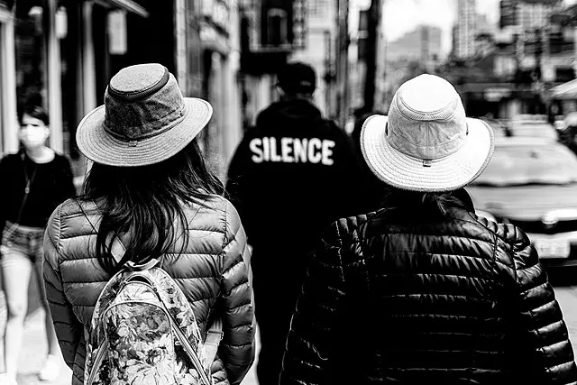 Two ladies wearing Tilley hats balance the inscription "Silence" in an interesting way on a street in Toronto, Canada. Picture by Maksim Sokolov (maxergon.com); Wikimedia Commons
